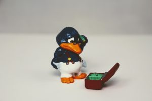 Auf dem Bild ist eine Enten-Figur zu sehen, die in eine leere Schatzkiste blickt.
